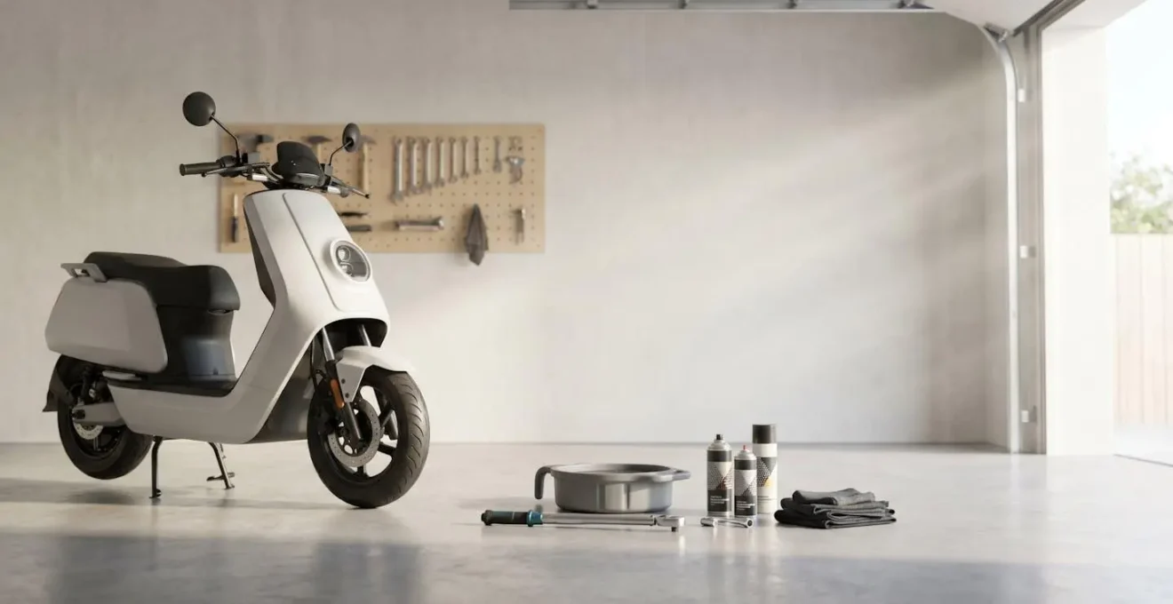 Scooter sur béquille centrale dans un garage avec outils d'entretien disposés au sol