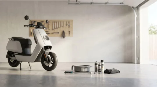 Scooter sur béquille centrale dans un garage avec outils d'entretien disposés au sol