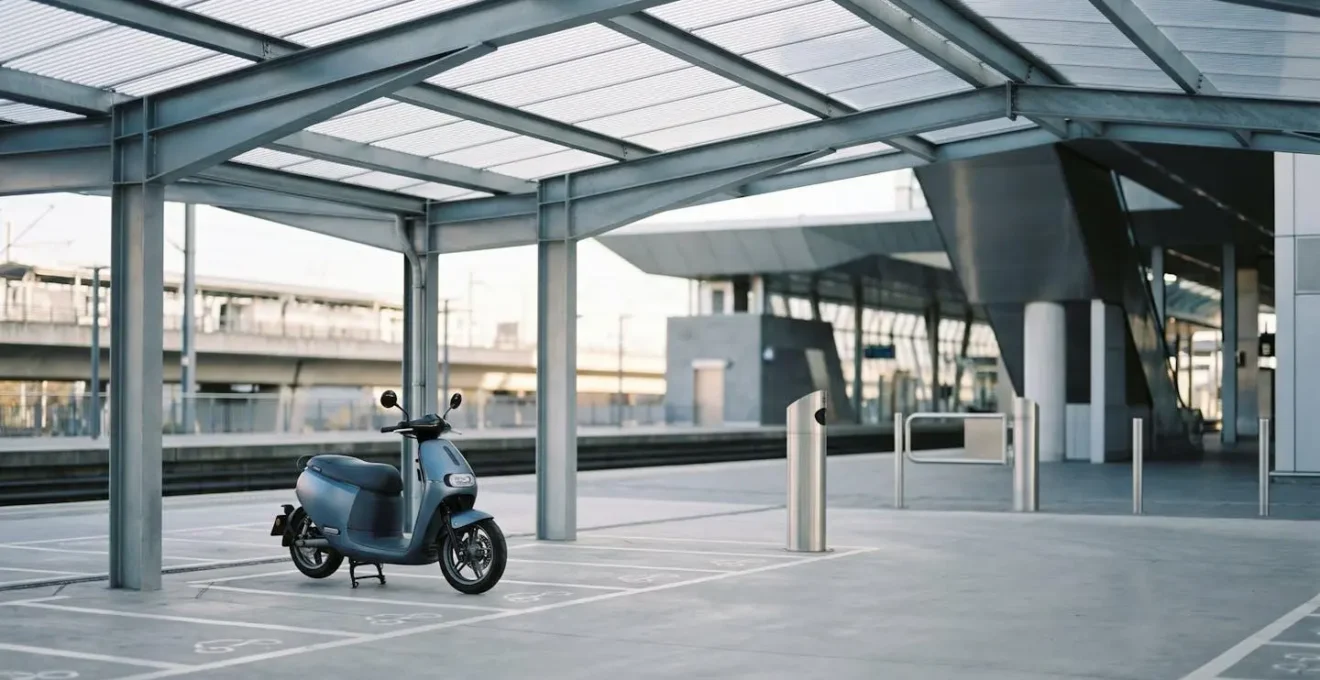 Scooter garé dans un parking sécurisé de pôle multimodal près d'une gare