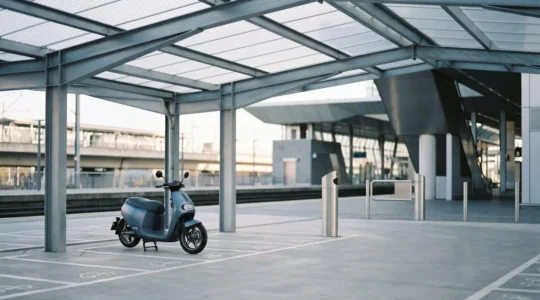 Scooter garé dans un parking sécurisé de pôle multimodal près d'une gare